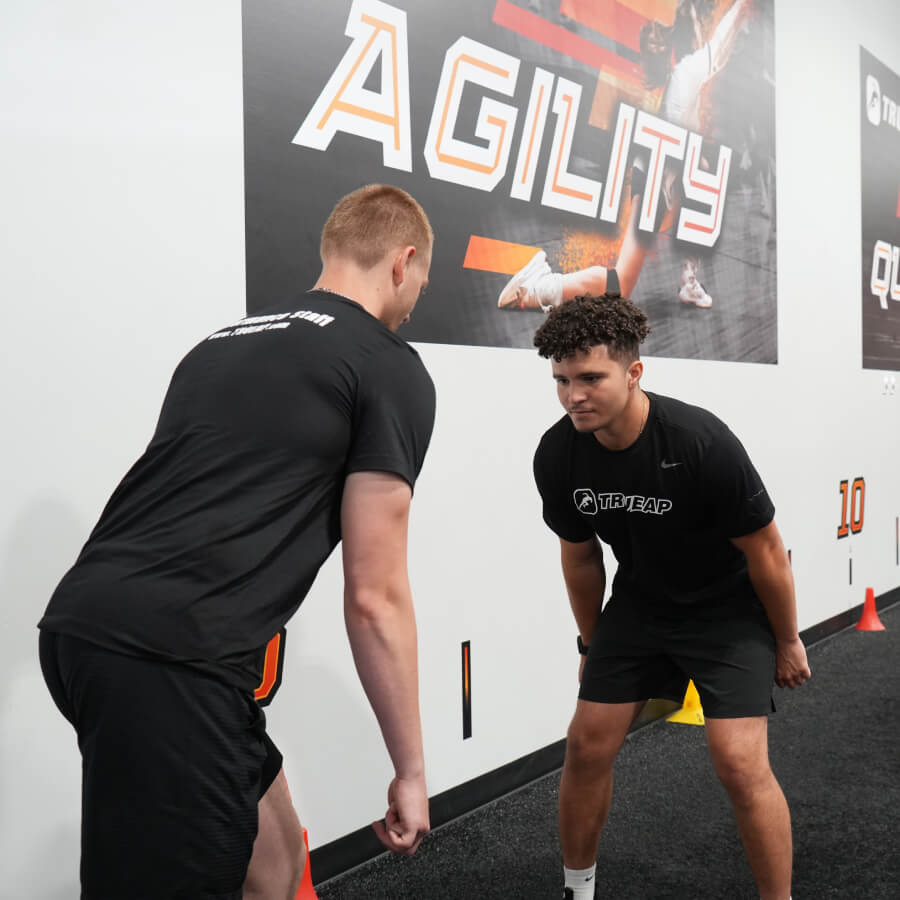 Two boys in black shirts prepare to run on indoor turf