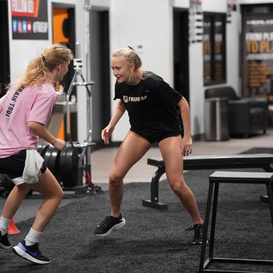 Two girls hover just above the ground on indoor turf.